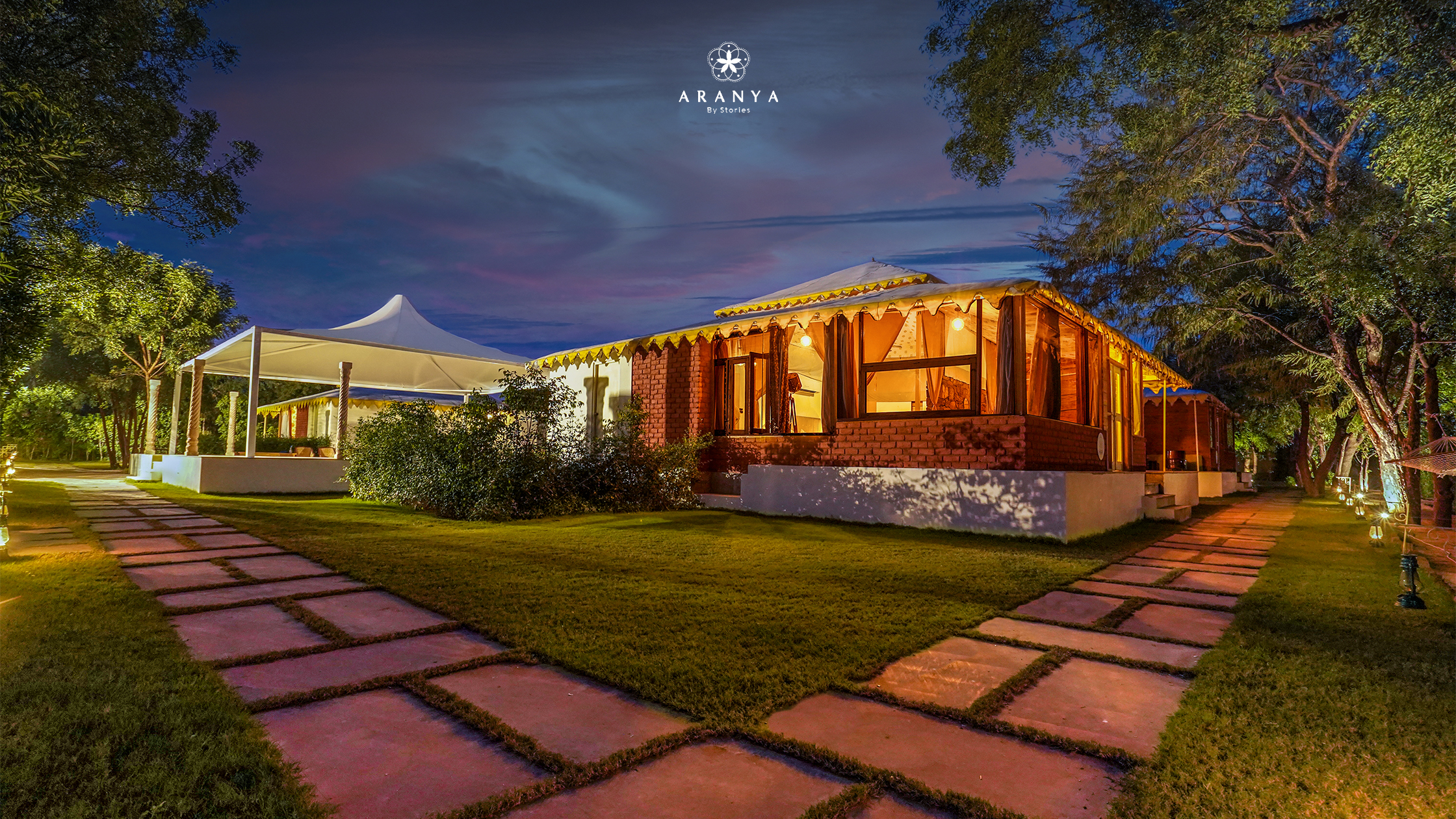 Luxury tent villa surrounded by lush gardens at Aranya by Stories during twilight